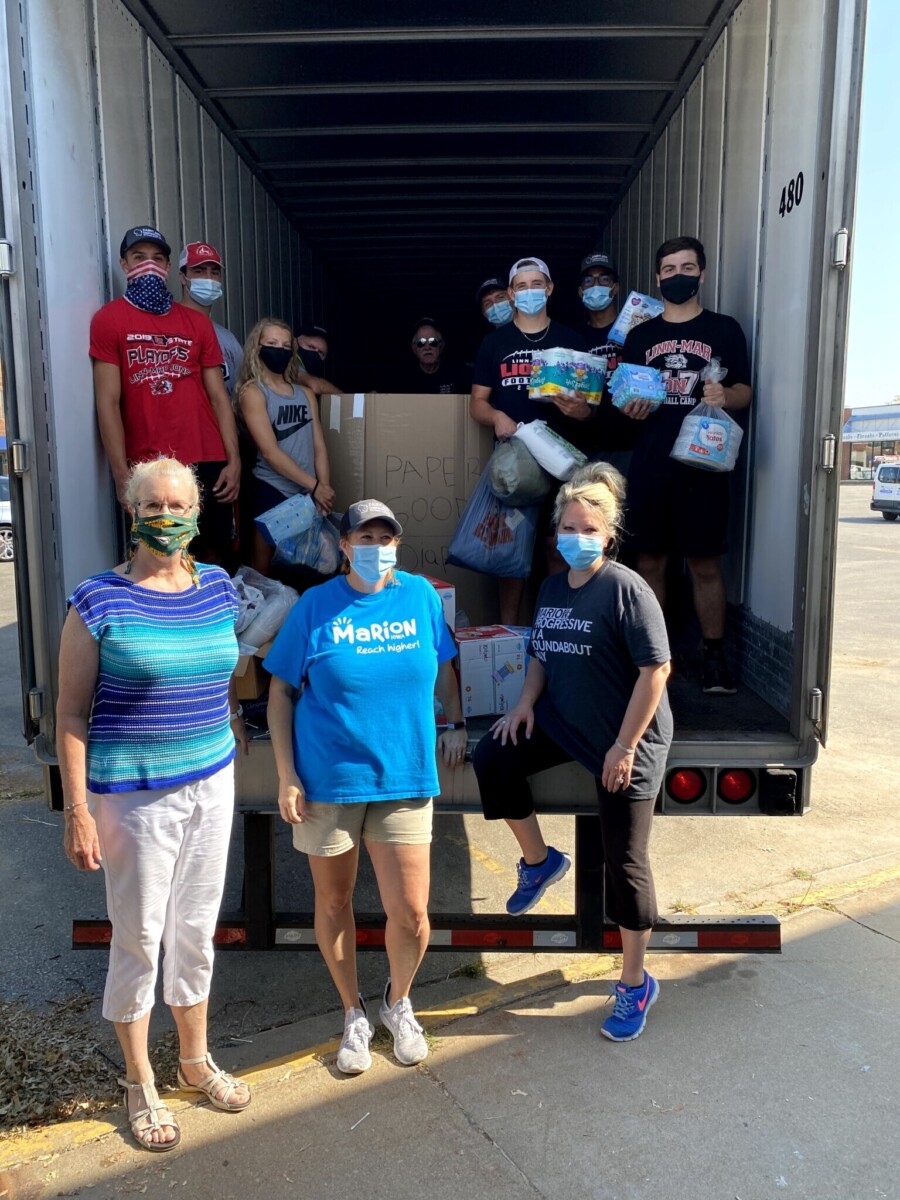 A group of people wearing masks pose in front of a truck