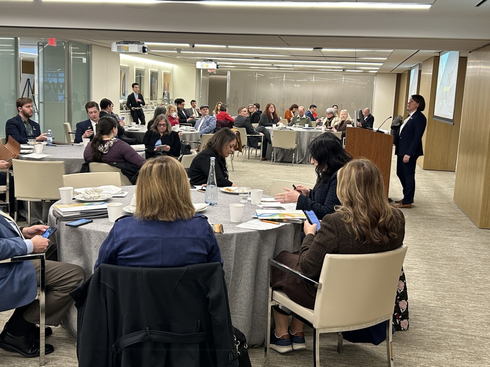 Participants sitting at round tables listening to a presentation