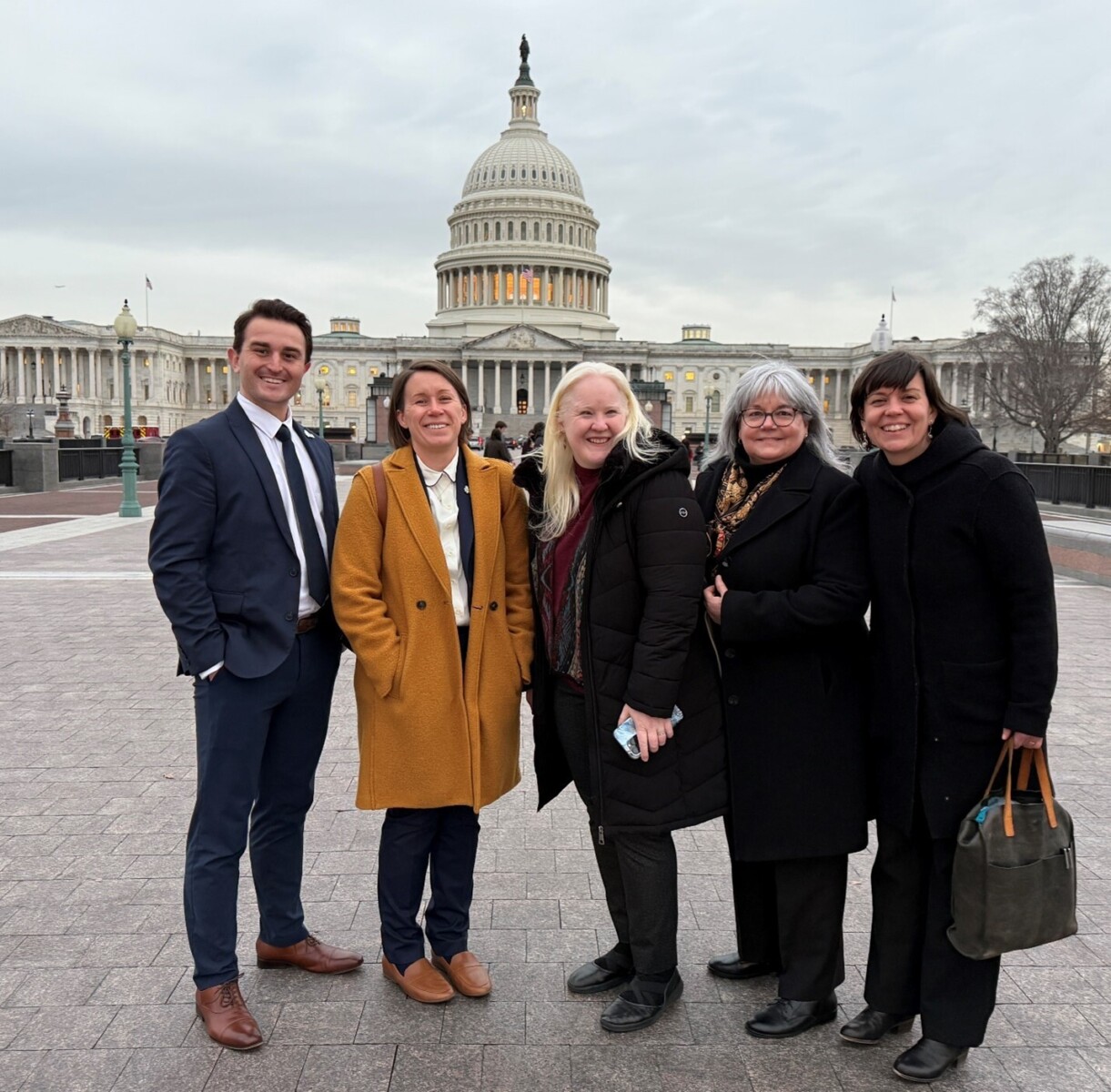 Five people posing in front of the Capitol building