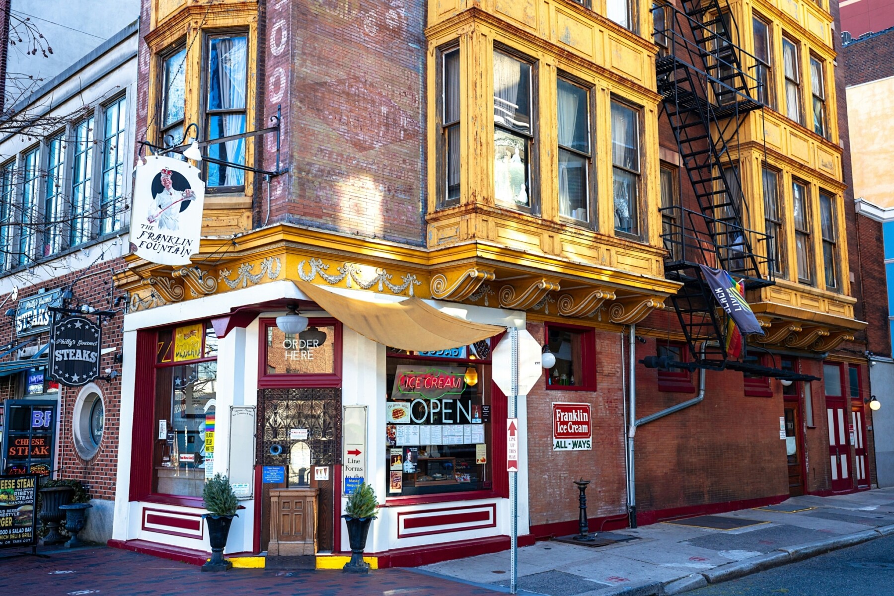 Historic tenement housing with bay windows, red brick, and ground floor retail