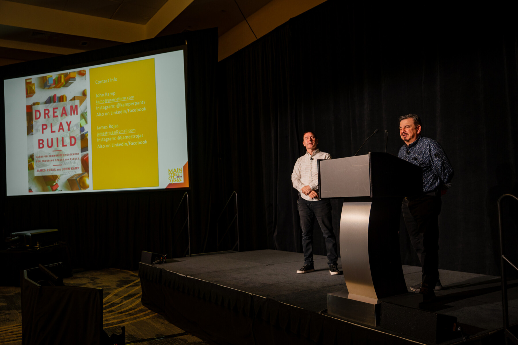 John Kamp and James Rojas presenting a slide showing their book, "Dream, Play, Build"