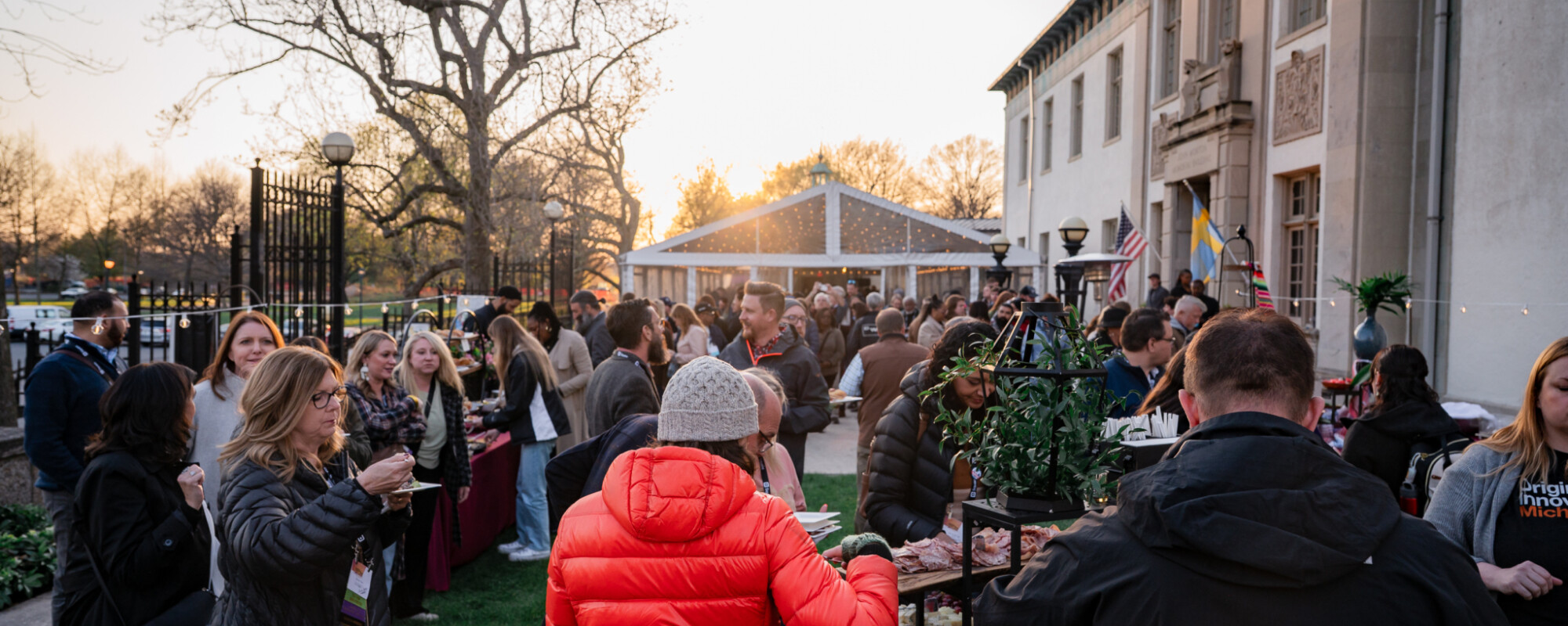 People in a park next to a historic building enjoying small plates and bites