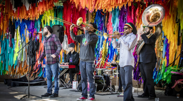 A jazz quartet playing on a stage with a vibrant, colorful background.