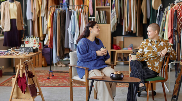 Two people sitting at a table drinking coffee inside a clothing store