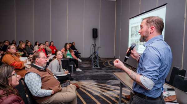 A man speaks to a large audience of people listening intently.