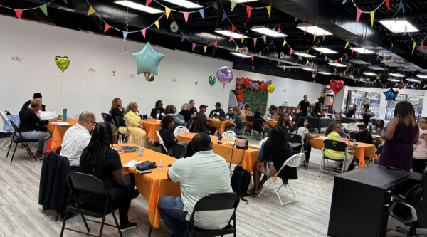 Mesas de personas en un acto en una sala decorada con banderines y globos