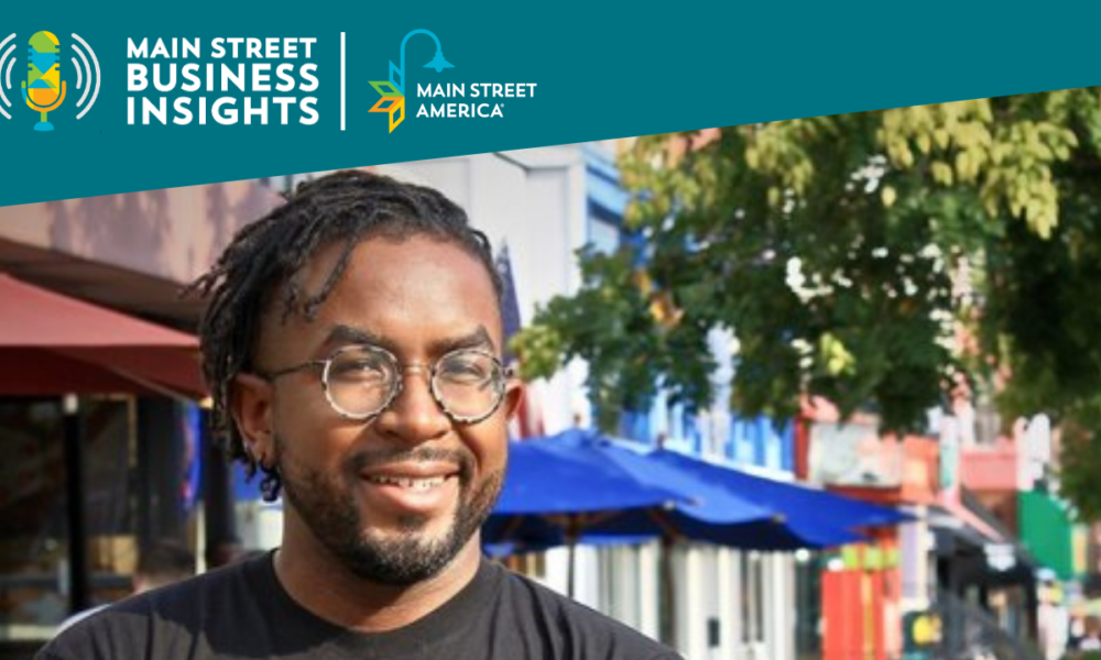 A man wearing glasses and a t-shirt reading, "Chocolate City" stands in front of an outdoor downtown street scene.