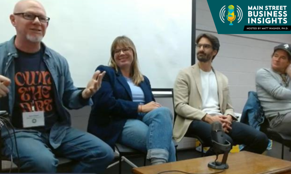 Panel of four people sitting in front of video screen.