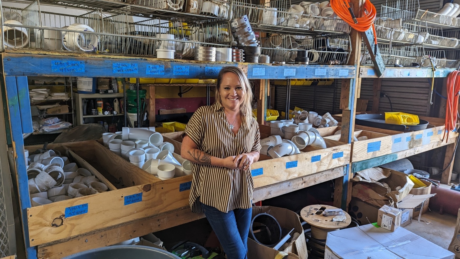 A young woman standing in a room with plumbing components.