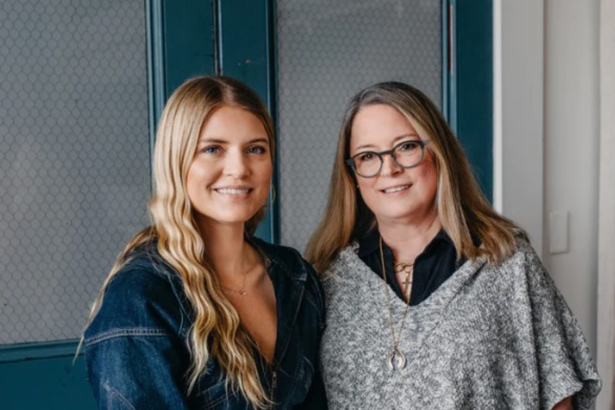 Photo of two smiling women in front of a blue door.