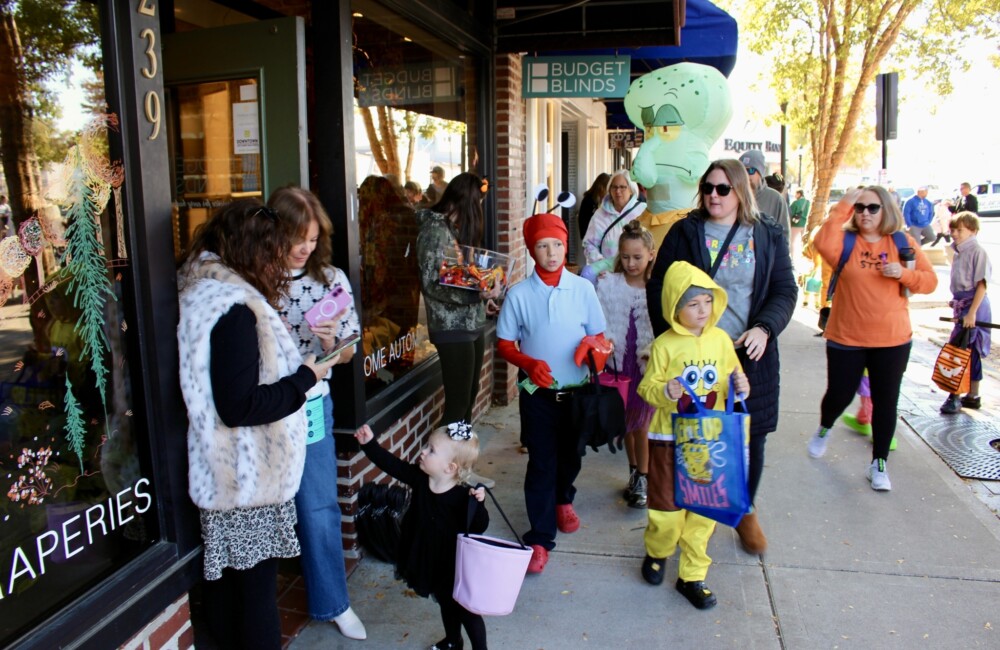 Children dressed as Sponge Bob Square Pants characters trick or treat at a downtown business