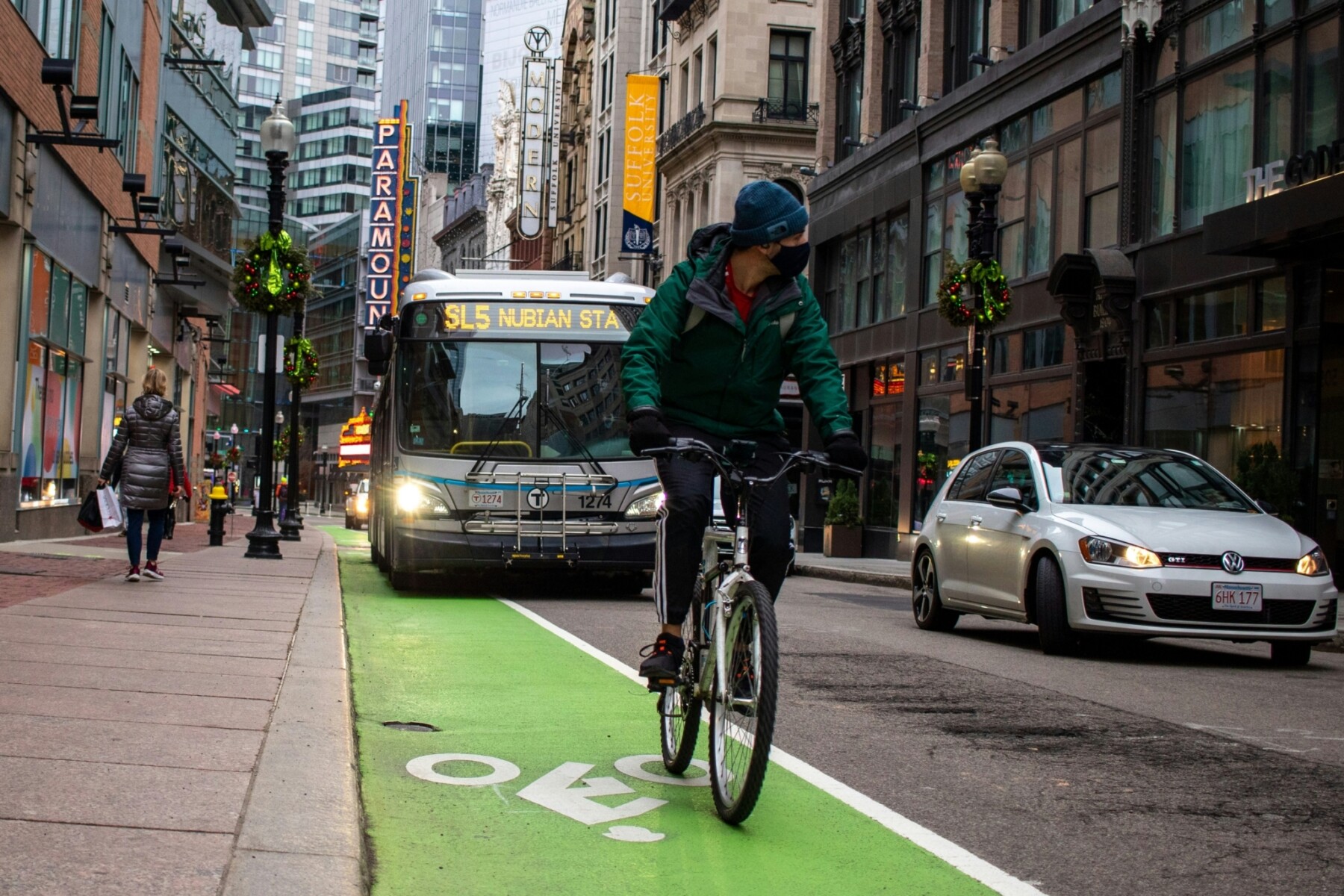 En Boston, un hombre circula en bicicleta por un carril bici mientras un autobús circula por el carril contiguo.