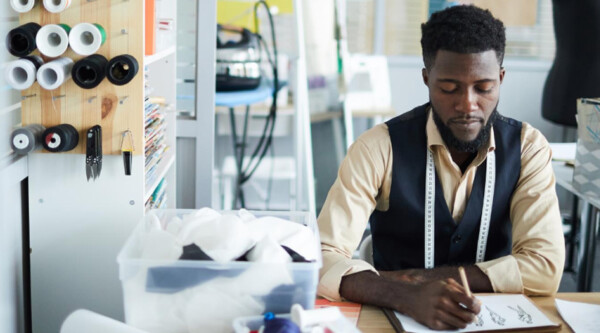 A man sitting at a work bench writing on a piece of paper