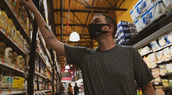 A man wearing a face mask browses items on shelves