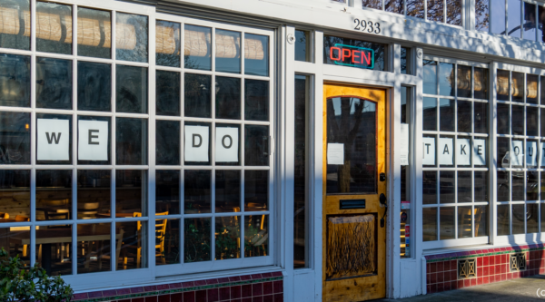 Small local restaurant with the a sign saying "we do take out" in the window