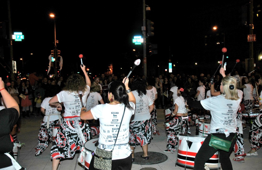 Drummers perform for a crowd at night.