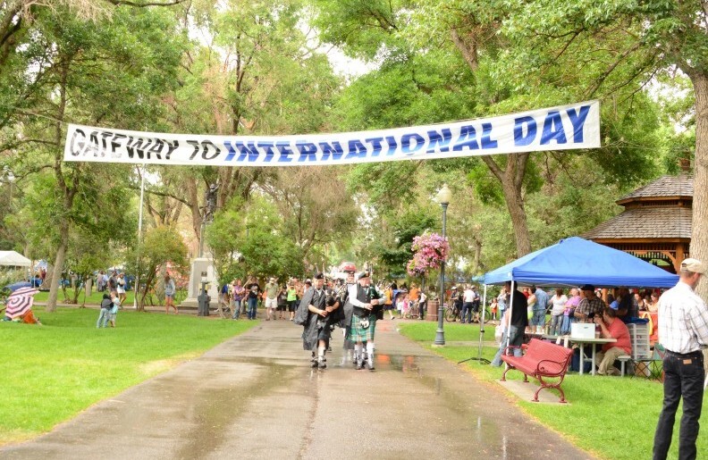 Bagpipers walk underneath a through a park.