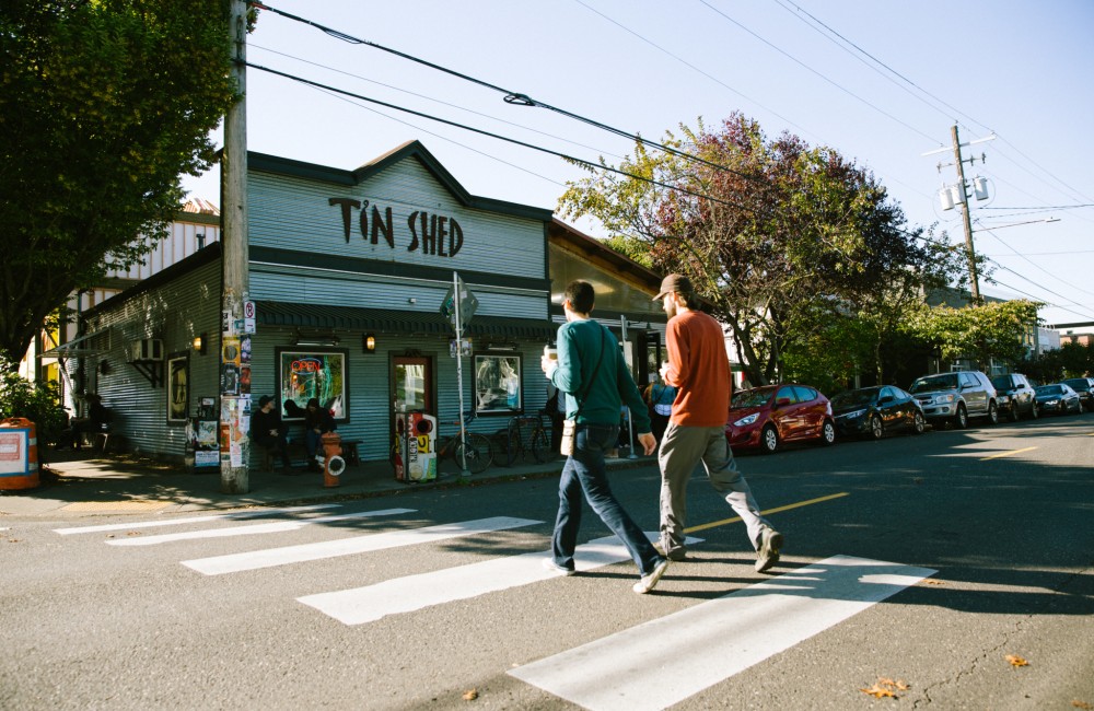 Two people cross a street towards a restaurant.