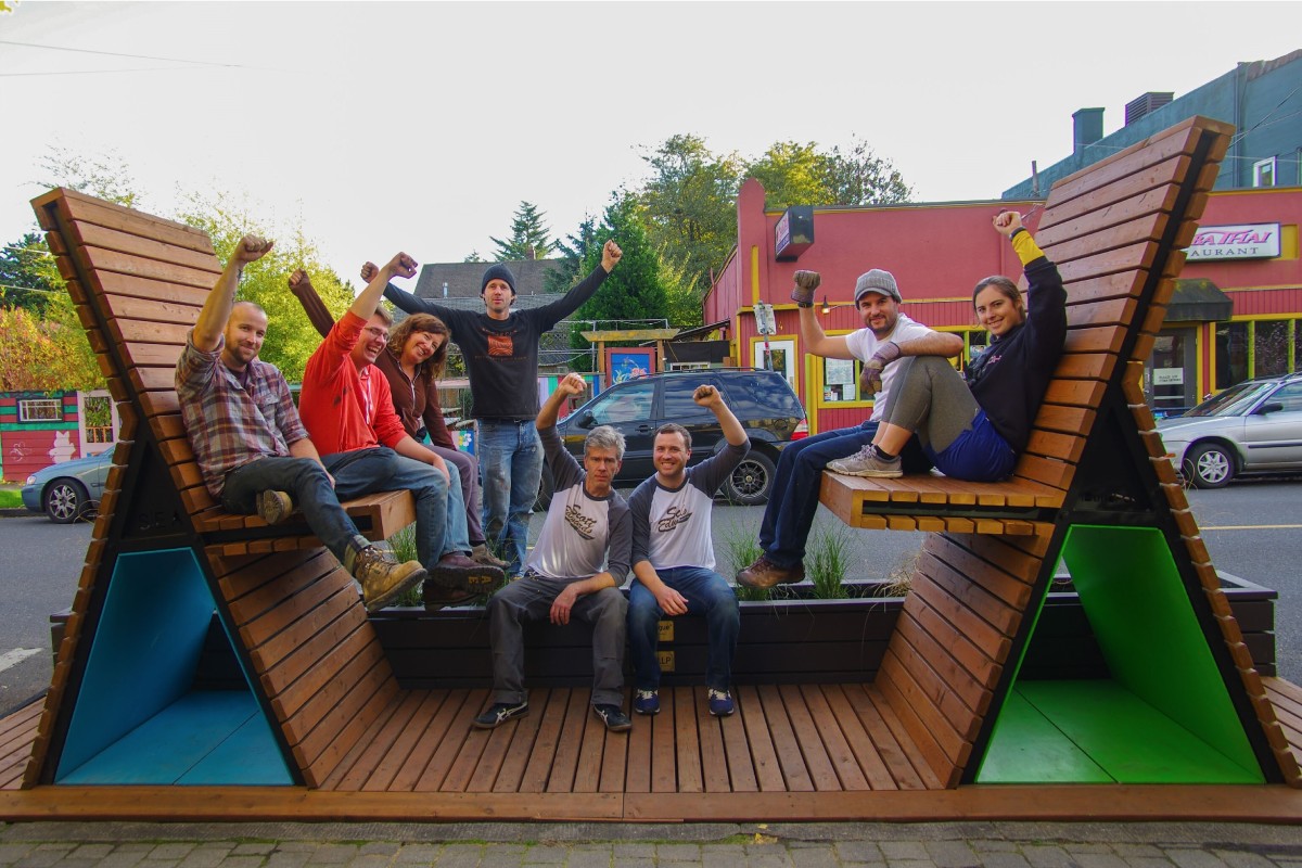 People gather inside a parklet with fists raised in celebration.