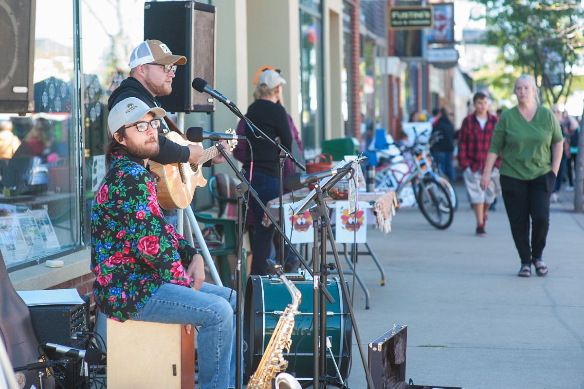 Musicians perform on a sidewalk while visitors walk by.
