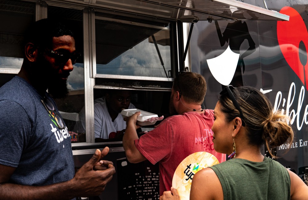 Customers wait to place and pick up orders at a food truck.