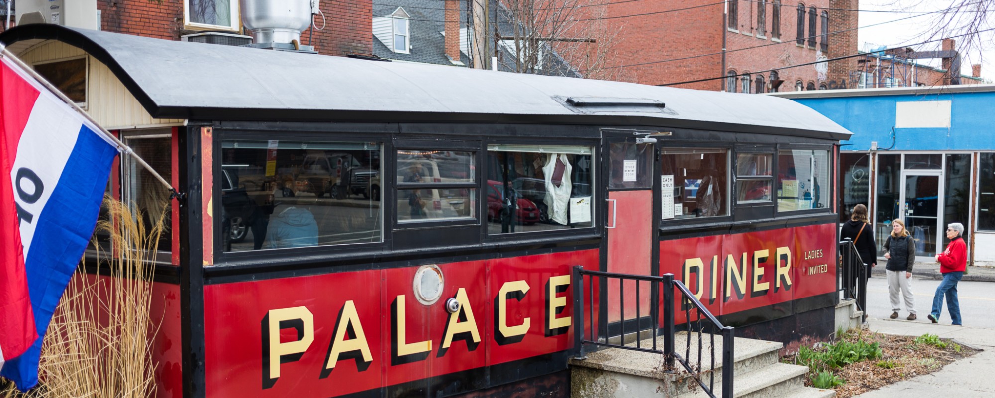 People stand outside an old railroad car that is home to a diner.