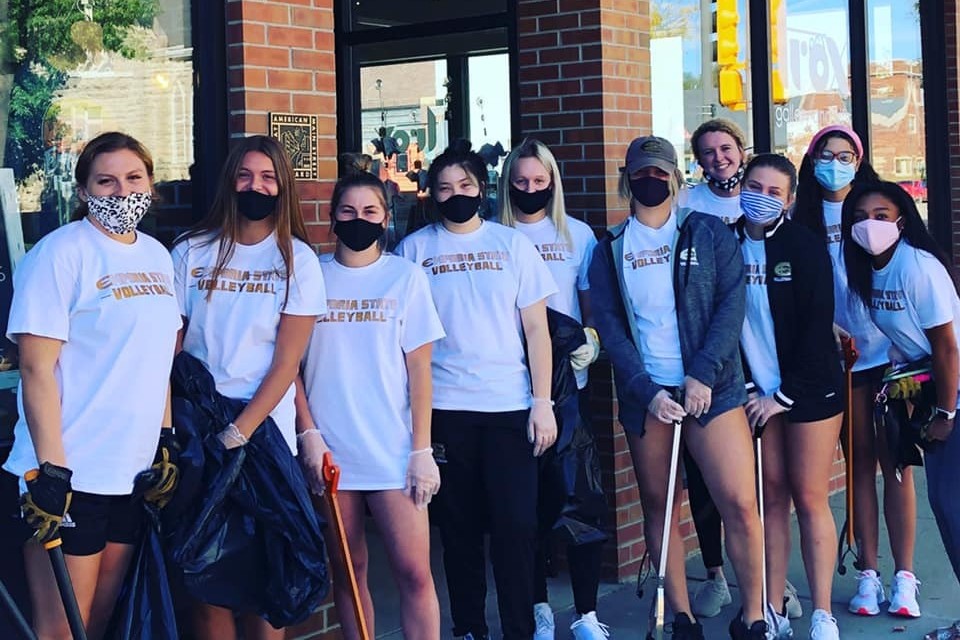 A large group of young women wearing face masks pose in front of the Emporia Main Street office.