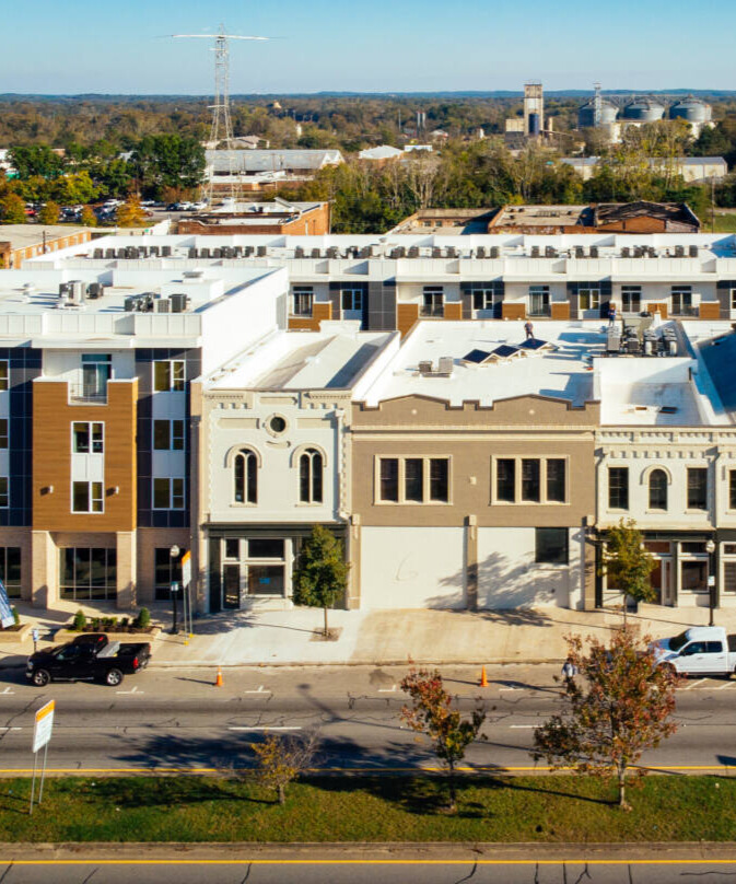 Aerial view of a street with commercial and upper story residential buildings.