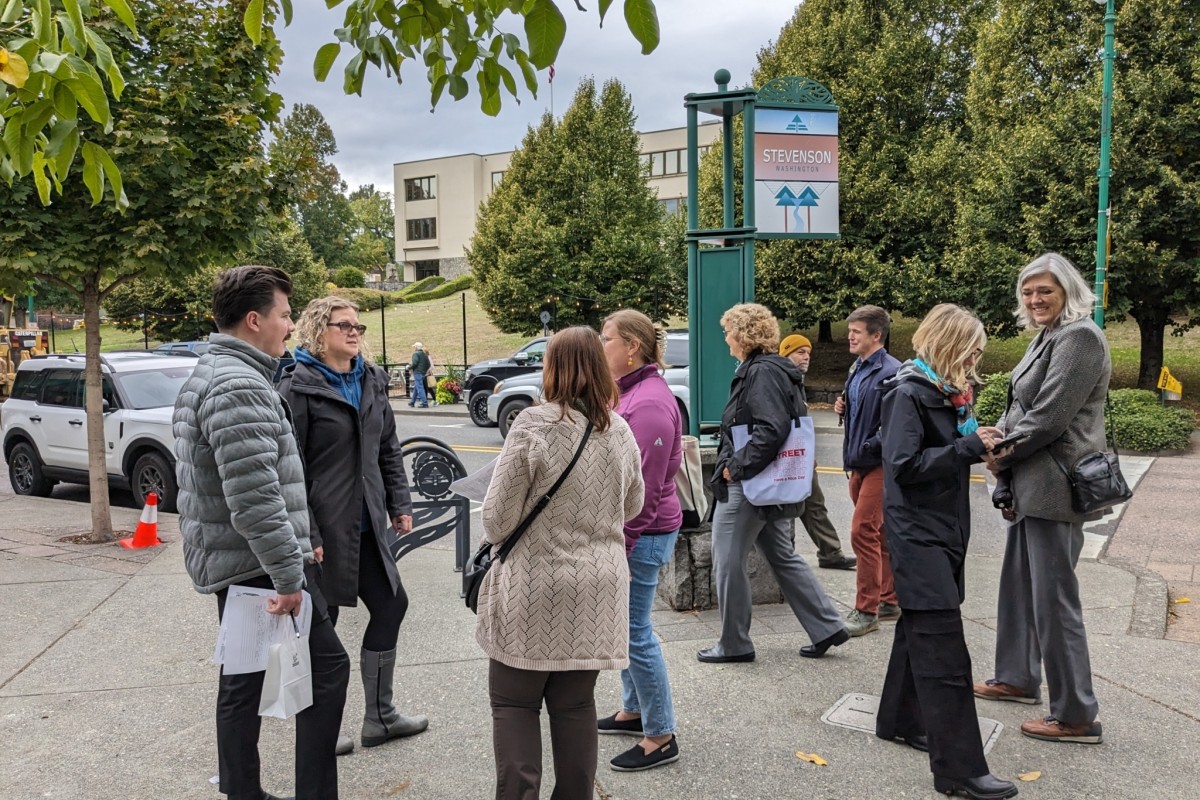 People gather in small groups on a sidewalk.
