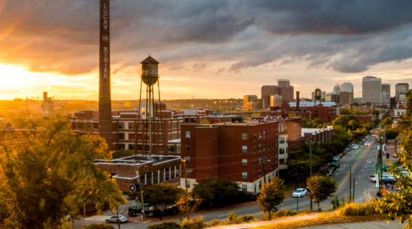 Sun setting behind a brick building-lined street.