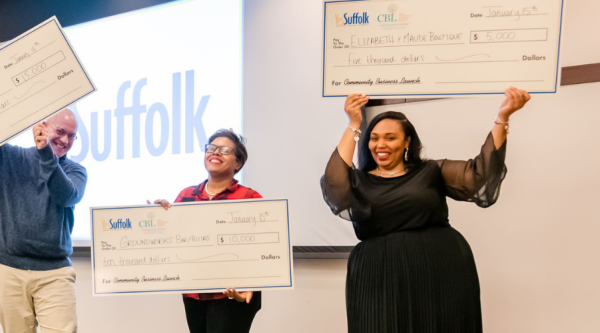 People hold up oversized checks.