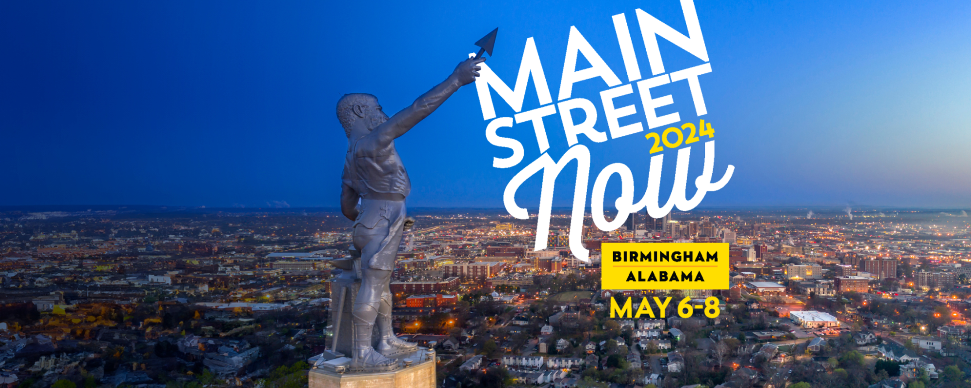Vulcan Statue with illuminated city of Birmingham skyline in the background. The statue's raised spear points to the Main Street Now 2024 logo in the upper right corner.