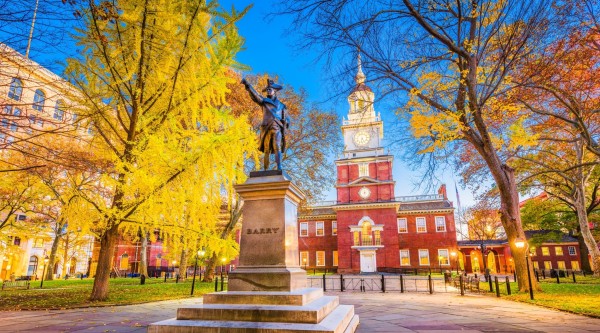 Bronze statue on a tall pedestal with Independence Hall in the background.