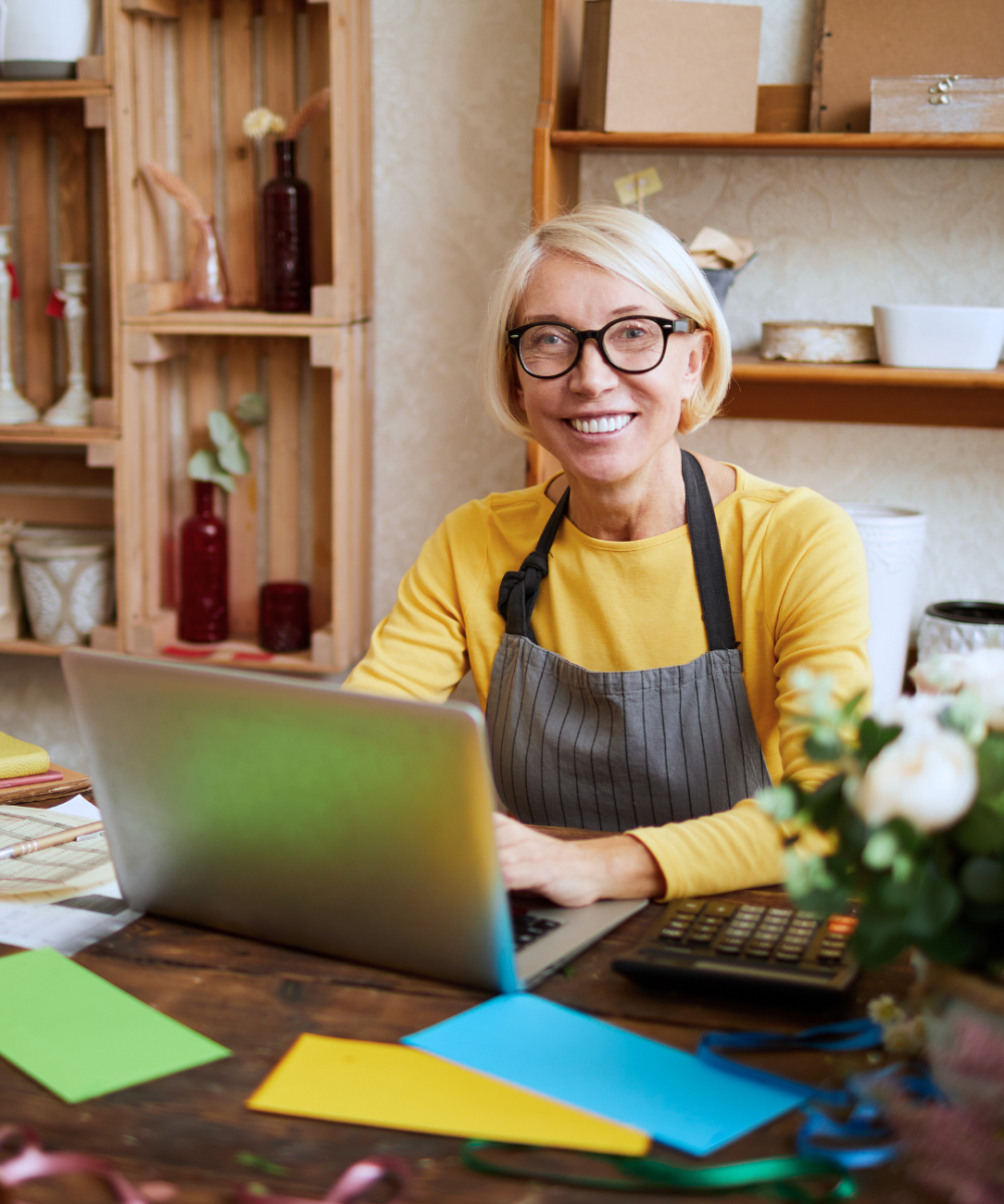 Stock smiling woman at desk in office with laptop computer open typing