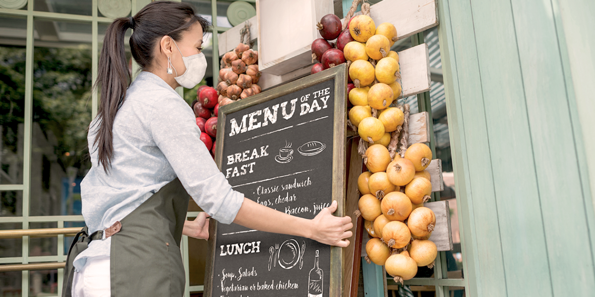 Woman hanging a chalkboard menu outside a small business