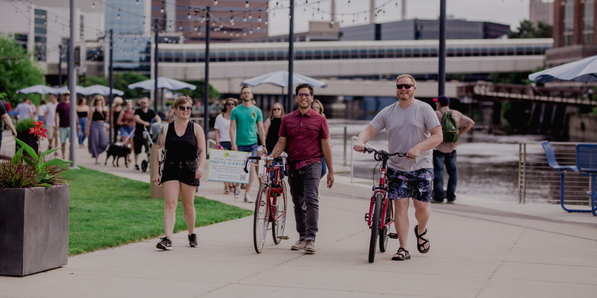 People walking their bikes across a downtown plaza