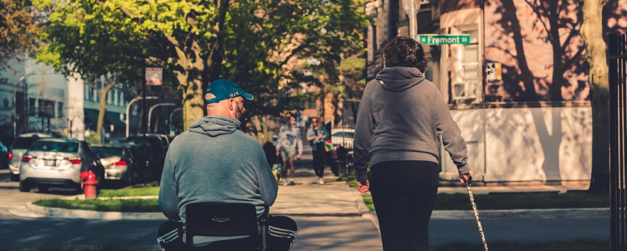 A person using a wheelchair and a person using a cane walk down a sidewalk in Chicago, Illinois.