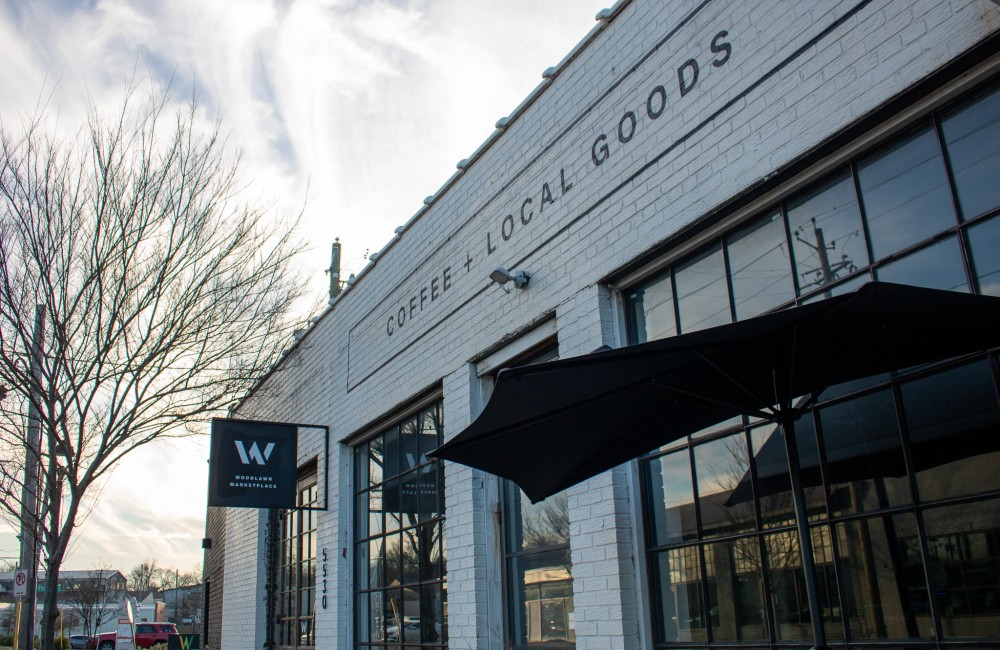 Exterior of a brick building with lettering on the façade that reads "Coffee + Local Goods."