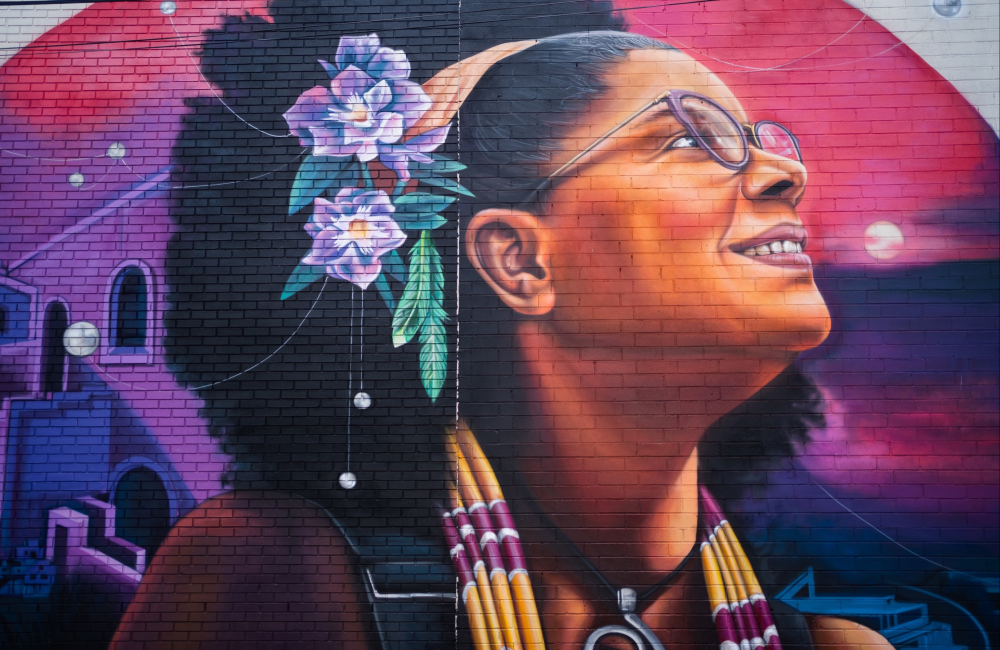 Vibrant mural featuring a profile of a Black woman wearing flowers in her naturally-styled hair.