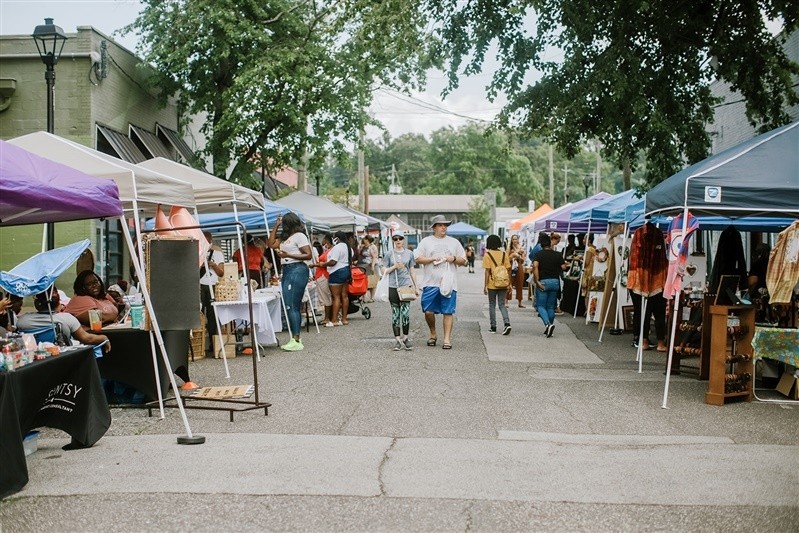 People stroll down an passageway created by pop-up vendor booths.