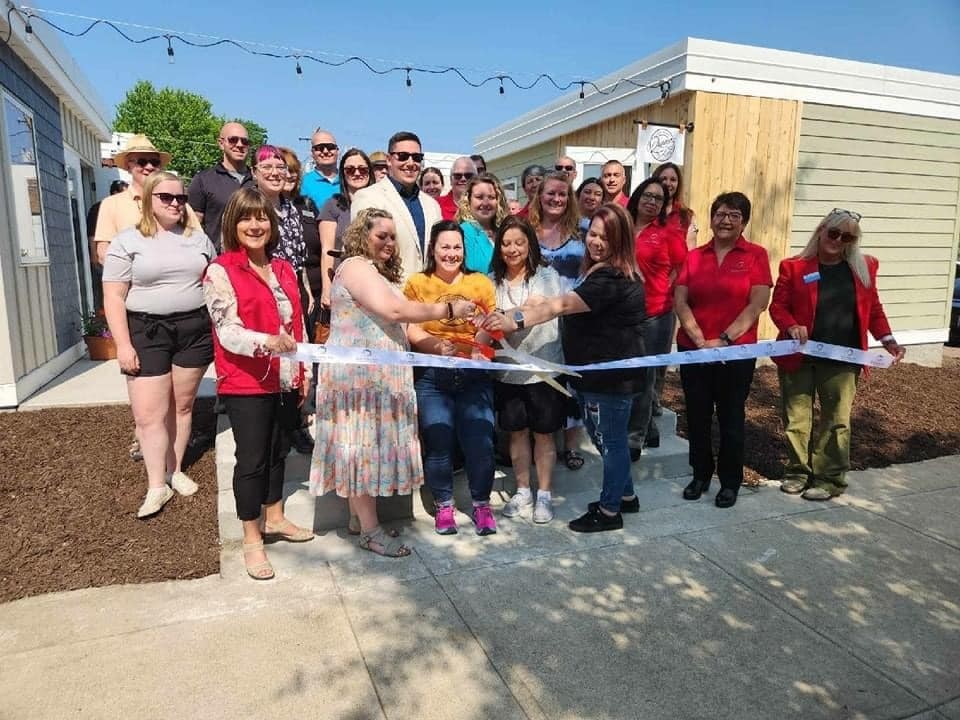 A large group of people posing at a ribbon cutting to open the micro retail space