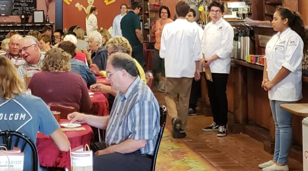 Group of eat in a restaurant with a sign on the back wall reading, "Rustic Brew."
