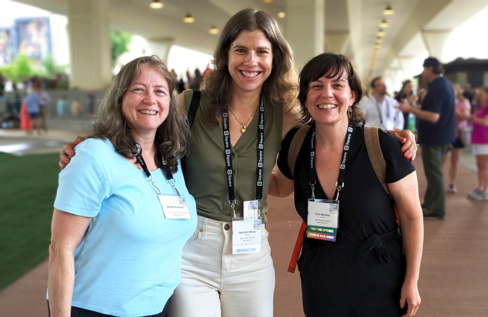 Three women stand side-by-side and smile.