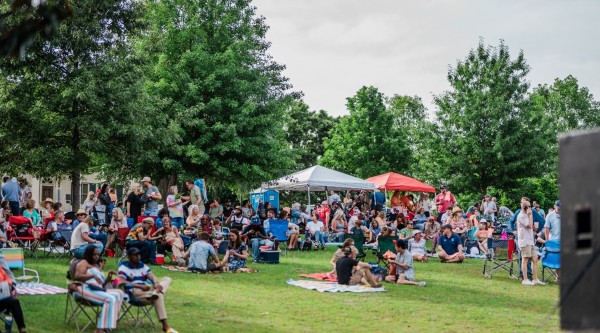 People sitting on chairs and picnic blankets at an outdoor concert