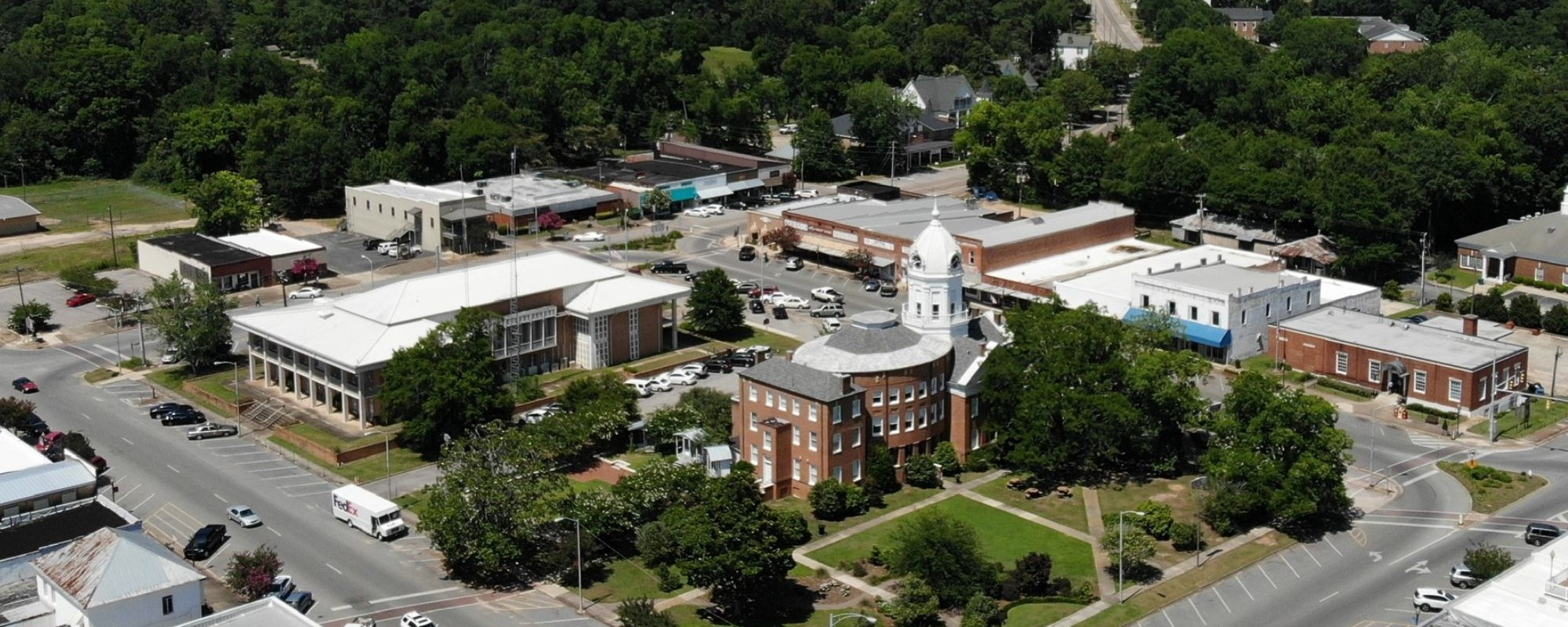 Ariel view of a small historic downtown with brick buildings surrounding a central square.