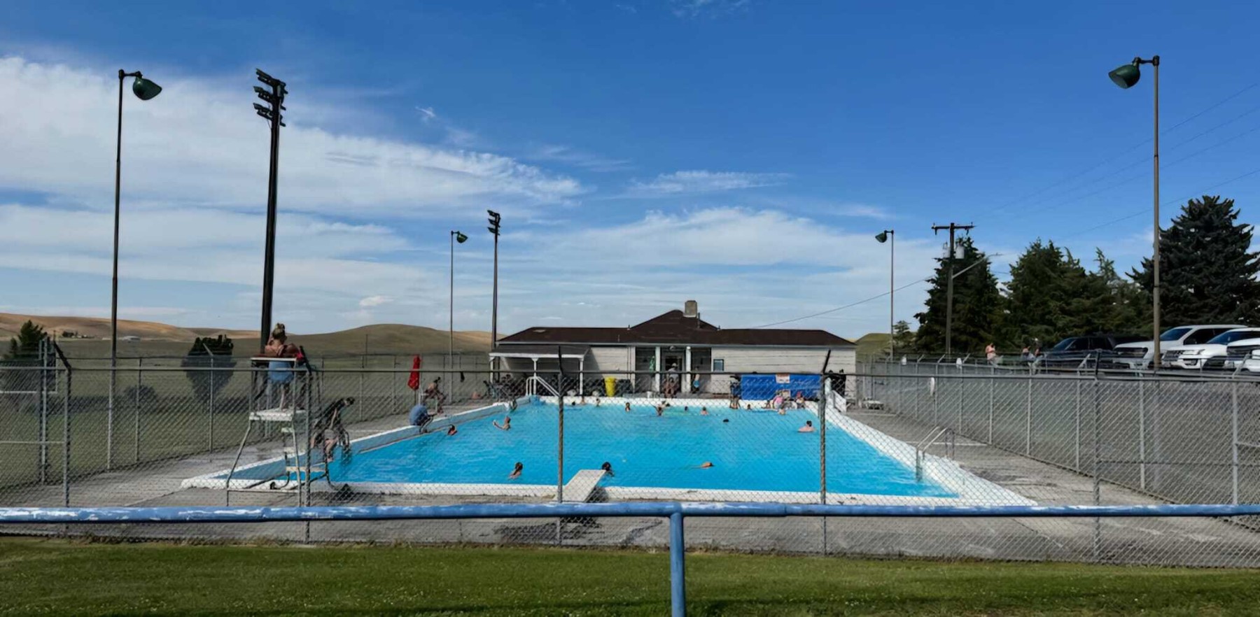 An outdoor pool with a small building and a wire fence