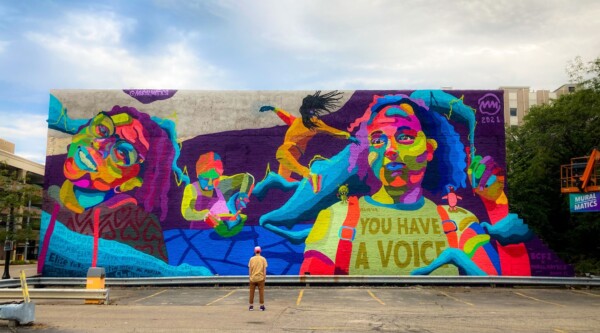 A large colorful mural featuring the faces of children and the words "you have a voice"