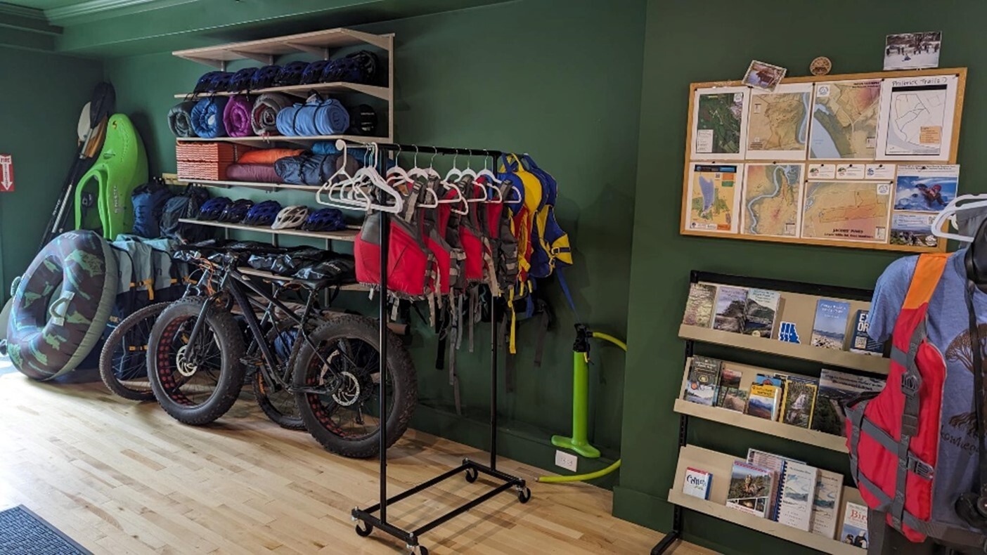 A wall of outdoor gear including mountain bikes, kayaking equipment, and maps