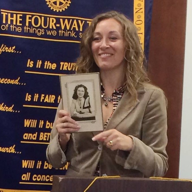 A woman holds up a black and white photo of another woman