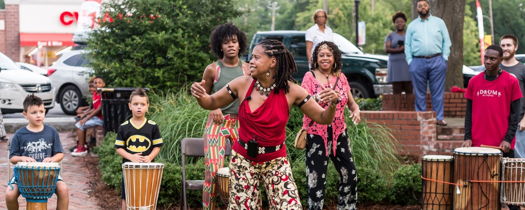 A woman dances while children play drums at a musical celebration